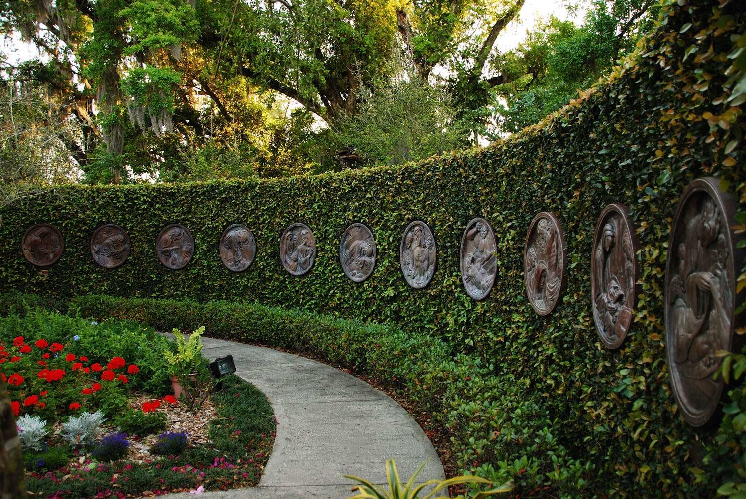 curved bush with metal oval sculptures in the greenery